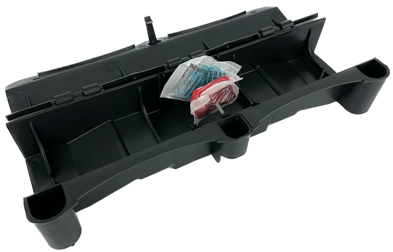 Otwarta, podłużna stacja deratyzacyjna z trutką w woreczkach umieszczoną na metalowym pręcie w centralnej części.