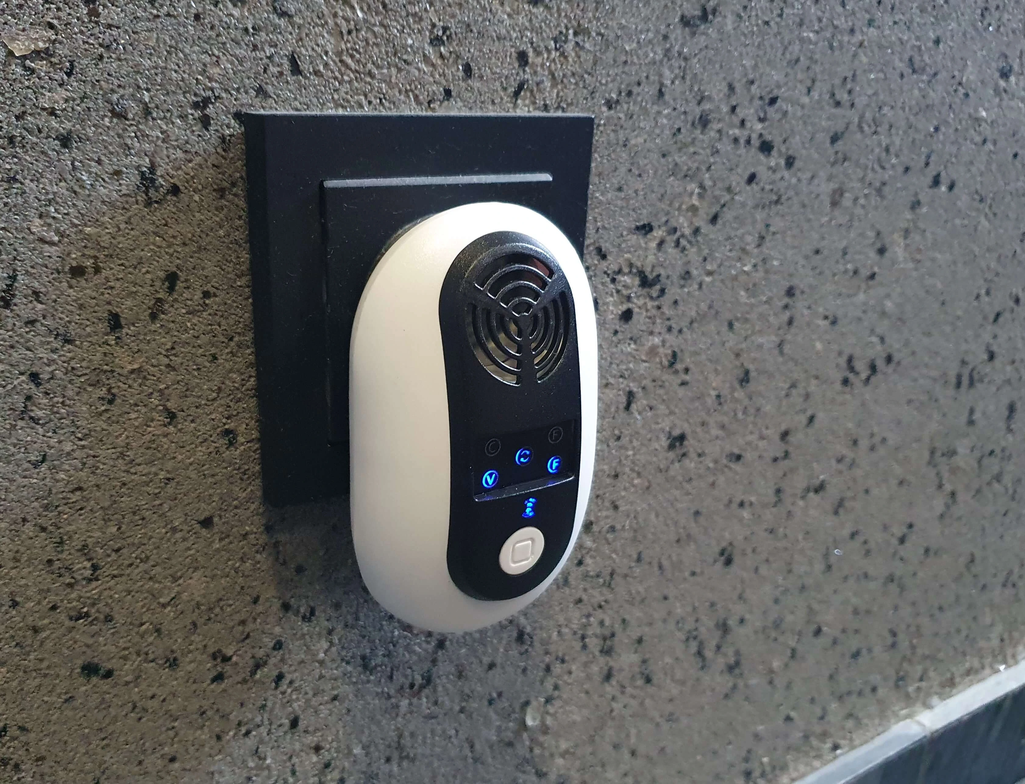 Odstraszacz gryzoni wpięty do gniazdka elektrycznego, z podświetlanymi ikonami trybów pracy i wylotem głośnika ultradźwiękowego.