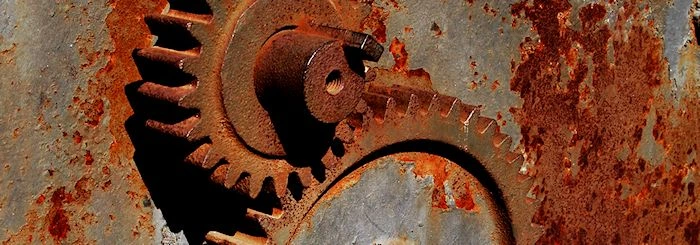 Zardzewiałe koła zębate na tle skorodowanej metalowej powierzchni.