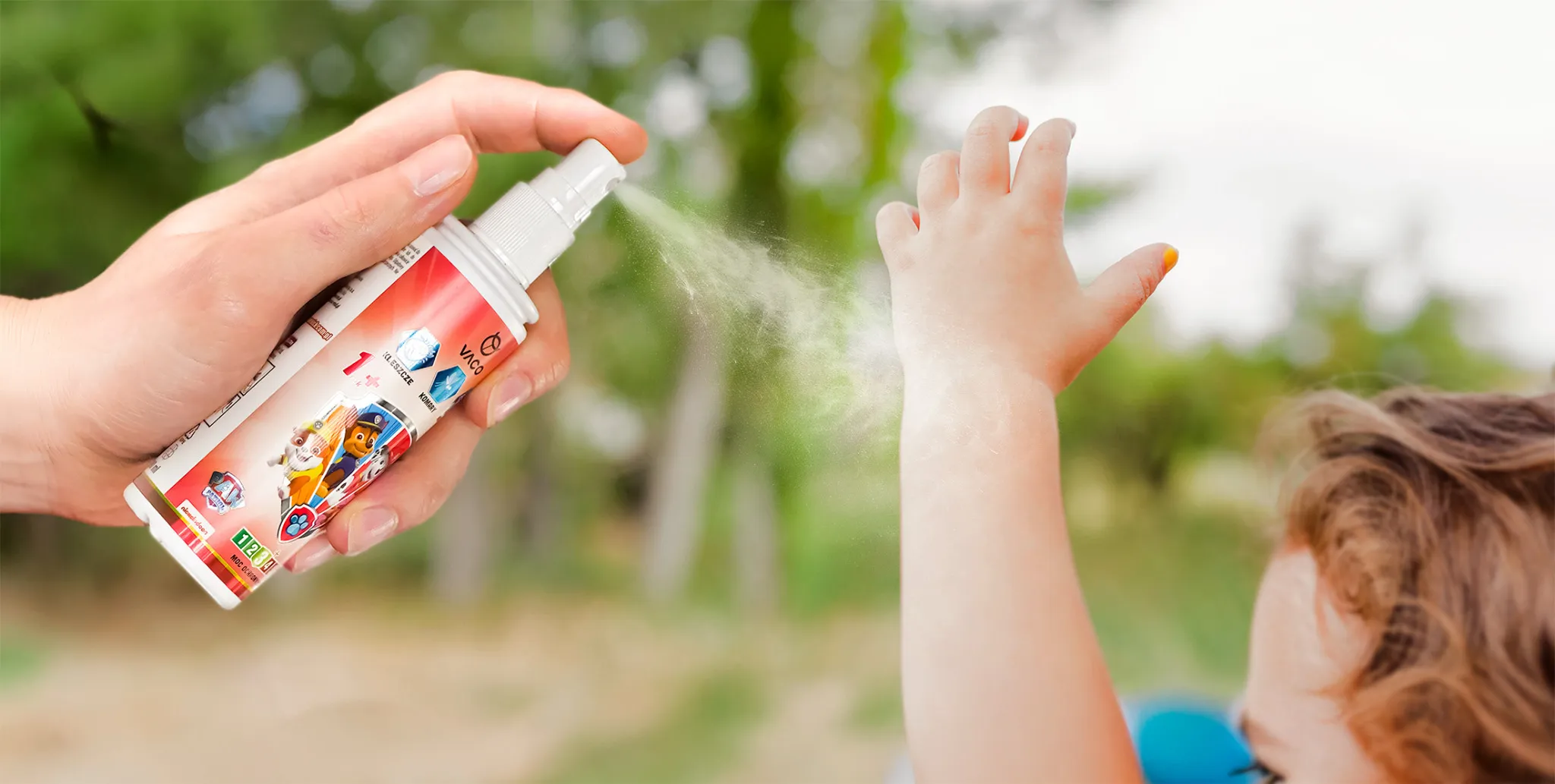 Spray przeciw kleszczom i komarom Vaco dla dzieci od 1. roku życia, aplikowany na rękę dziecka; opakowanie z postaciami z Psiego Patrolu