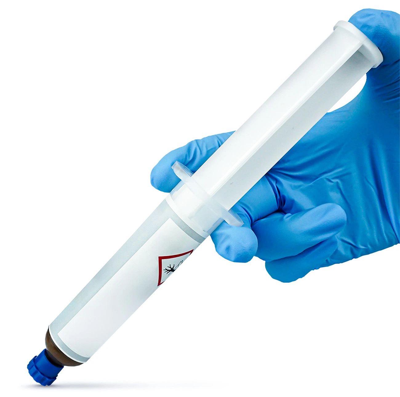 Strzykawka z żelową trutką na owady, trzymana w dłoni w niebieskiej rękawiczce ochronnej; na etykiecie widoczny symbol zagrożenia biologicznego.